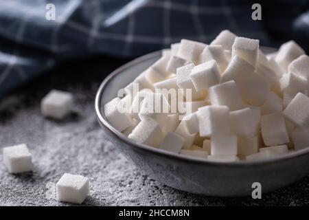 White sugar cubes in a blue bowl on the table. Stock Photo