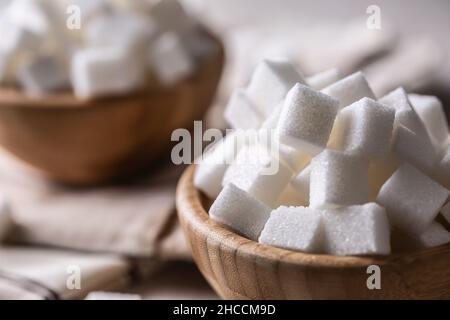White sugar cubes in a wooden bowl on the table. Stock Photo