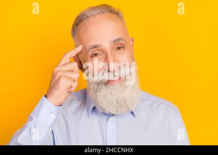 Photo of positive beard aged man finger head wear blue shirt isolated on yellow color background Stock Photo