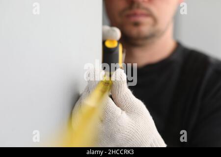 Male construction worker measuring size of wall with ruler closeup Stock Photo