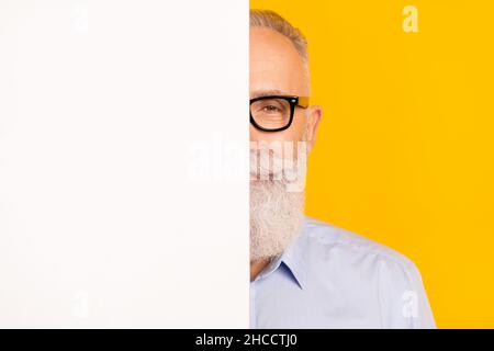 Close-up portrait of attractive bearded man hiding behind copy space board isolated over gray pastel color background Stock Photo