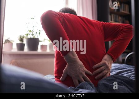 Senior man suffering from pain in back or reins at home Stock Photo
