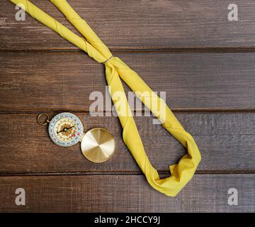 Yellow scarf of a scout and compass on wooden background Stock Photo