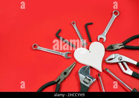Construction tools for repairs and whire Heart on a red background. DIY tools, Various carpentry. Top view with space for text. Valentines Day concept. Stock Photo