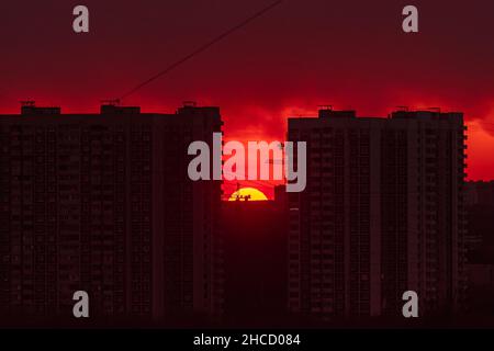 Sunset on the background of a construction crane. A bright red sunset against the backdrop of the construction of new houses in the Moscow Stock Photo