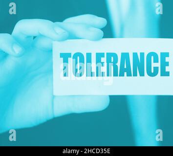 Tolerance words on a card in businessman hand. Social concept against discrimination at workplace. Stock Photo