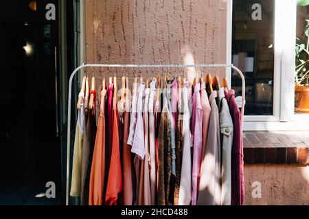 Fashionable clothes hanging on a rail outside a shop Stock Photo