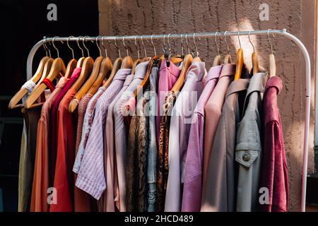 A closeup shot of colorful fashionable clothes hanging on a rail outside a shop Stock Photo