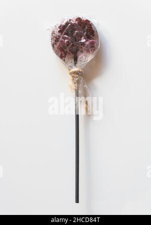 Lollipop on a stick in a transparent wrapper on a white background. Stock Photo