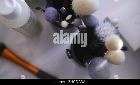 Close up of set of make up tools on white table background. Top view of many different brushes for make up in glasses, beauty industry concept. Stock Photo