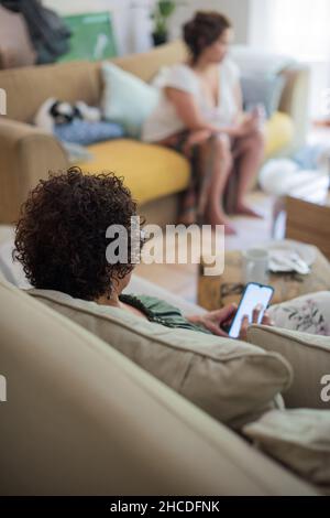 Woman using her mobile phone with blurred person in background Stock Photo