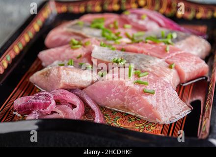 Red herring with onions and herbs on tray. Close up Stock Photo