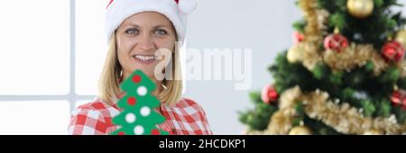 Woman builder in santa claus hat on background of christmas tree Stock Photo