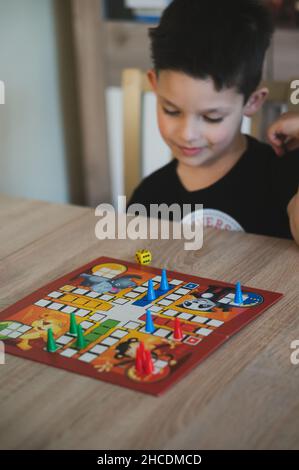 Boy playing the German board game Mensch Aergere Dich Nicht (Man, Don't Get Angry) on a table. Stock Photo