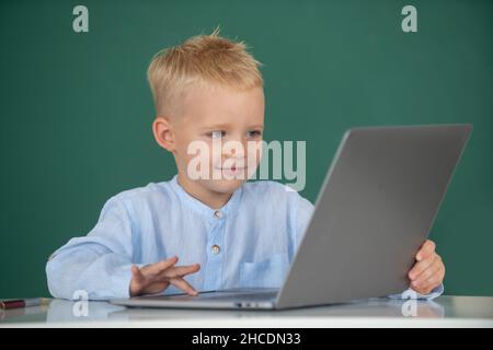 School boy learn lesson sitting at desk, studying online e-learning use internet. Genius child programming, computer training. Stock Photo