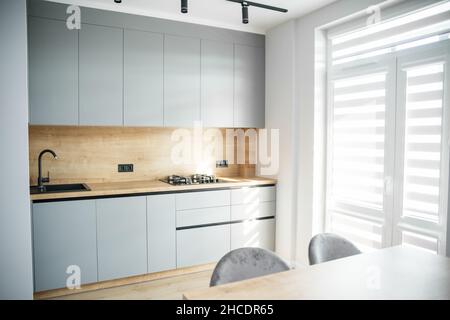 Wooden floor. Table with chairs. TV on the wall. Sunlight. Stock Photo