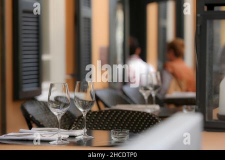 Atmospheric image of an outdoor cafe with out of focus people in the background and a coffee table in focus in the foreground. Photographed in Israel Stock Photo