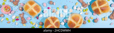 Bright high-colored Easter festive background. Blue background with traditional Easter sweets - hot cross buns, chocolate eggs sweets, colorful sugar Stock Photo