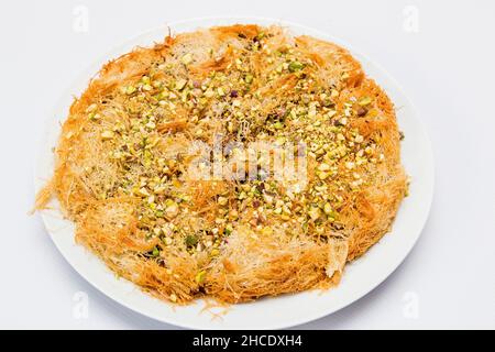 Knafeh [Knafe] is a traditional Middle Eastern dessert made with spun pastry called kataifi, soaked in sweet, sugar-based syrup, and typically layered Stock Photo