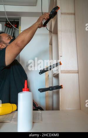 Man using clamps to hold workpiece gluing. DIY project at home. Stock Photo