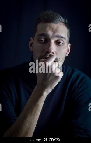 portrait of a pensive young man biting his nails looking away Stock Photo