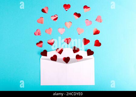 Valentine's Day layout. Red hearts pour out of an envelope on a blue background. Blank greeting card and envelope template for wedding Stock Photo
