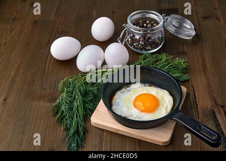 Fried egg in a small skillet with a stand, a bunch of dill Stock Photo