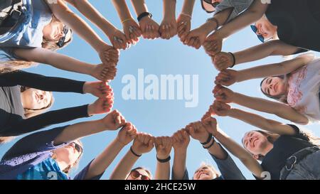 A group of girls makes a circle from their fists of their hands. Stock Photo