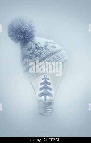 lamp with a winter wool hat and a illuminated Christmas tree Stock Photo