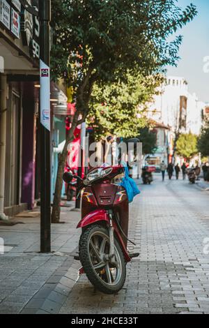 Parked motorcycle on a street in Turkey. Red motorcycle with blue bags hanging. Sunny winter weather. Stock Photo