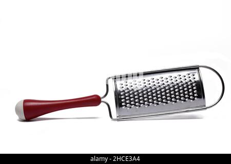 Close up of curved metal spice grater with red handle isolated on white background Stock Photo