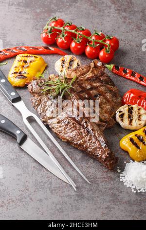 Beef T-Bone steak with grilled vegetables and seasoning on grey background close up. Vertical Stock Photo