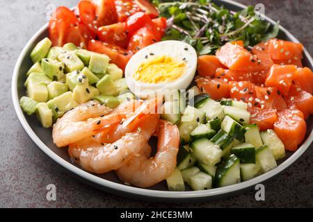 Organic breakfast of salmon, shrimps, eggs and fresh vegetables close-up in a plate on a concrete table. horizontal Stock Photo