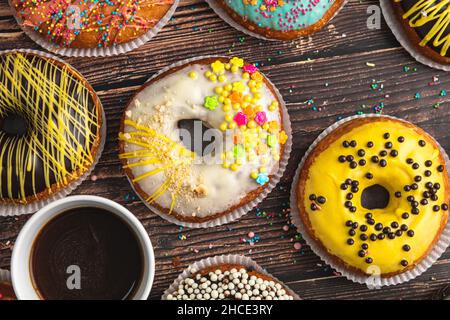 Top view of donuts in various colors and flavors on wooden table Stock Photo