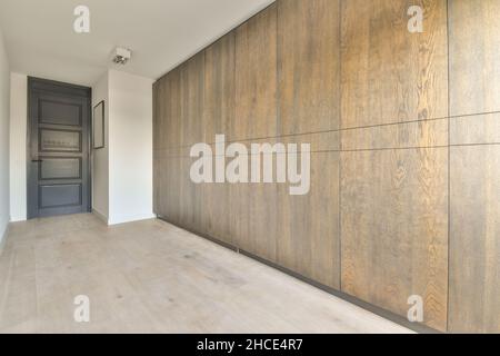 Interior of narrow light modern bedroom furnished with wardrobe placed on parquet floor near door Stock Photo