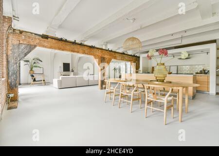 Dining zone furnished with table and chairs placed near balcony and sofa in spacious apartment in daylight Stock Photo