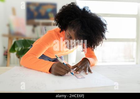 Concentrated African American female designer making drawing sketches with pen and ruler on paper Stock Photo