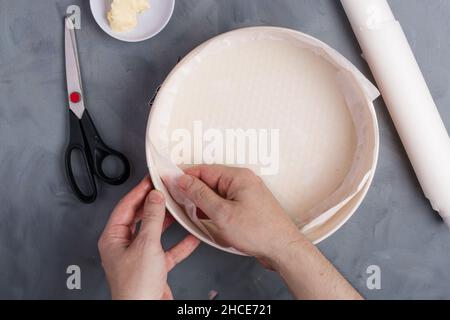 From above of crop unrecognizable female putting baking paper on bakery form while preparing cake Stock Photo
