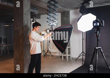Male standing and turning on modern octabox light in professional photo studio Stock Photo