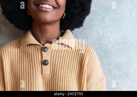 Crop of portrait of anonymous cheerful young African American female with Afro hairstyle on a gray background Stock Photo