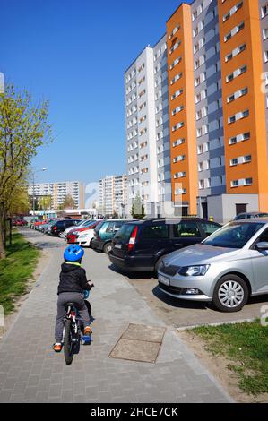 Vertical shot of the young boy riding a bicycle on a sidewalk. Stare Zegrze district Stock Photo