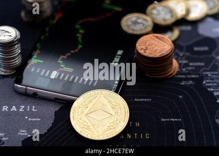 Stack of various bitcoins scattered on mobile phone display with financial chart on screen placed on world map Stock Photo