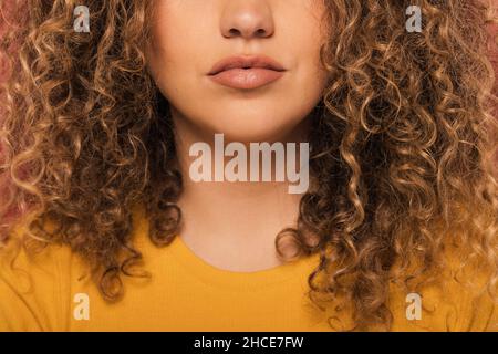 Crop unrecognizable Woman portrait with curly hair looking at camera while standing on pink background Stock Photo