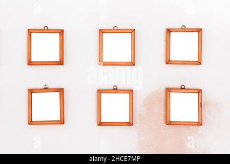 Collection of six empty wooden frames in shape of square hanging on wall Stock Photo