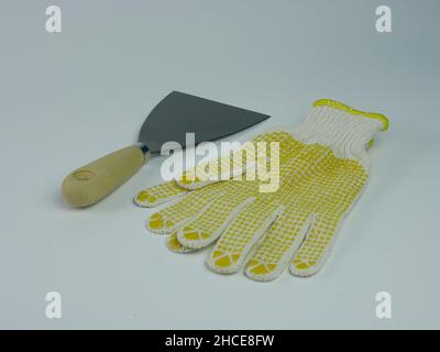 Scrapper or putty knife and work gloves isolated on white background. Stock Photo