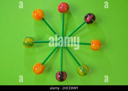 Tasty lollipops on green pastel color background. Set of realistic colorful lollipops on green plastic sticks. Summer and pop art concept. Top view Stock Photo