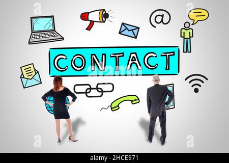 Contact concept drawn on a wall watched by business people Stock Photo