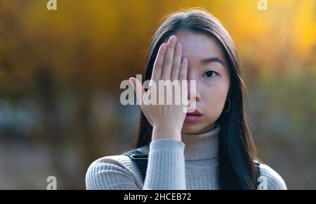 Asian young woman covering her eye with her hand. Do not want to see something. Stock Photo