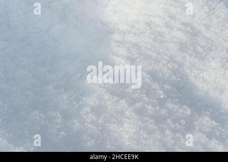 Sun shines on ground covered with snow forming small hills - closeup macro detail Stock Photo