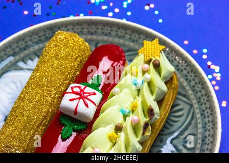Festively decorated eclairs in New Year's style 2022 lying on round gray plate. Stock Photo